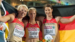 Die deutschen Speerwerferinnen Christina Obergföll (l, Silber) und Linda Stahl (r., Gold) sowie die Sprinterin Verena Sailer (100m, Gold) posieren mit der deutschen Fahne. © dpa - Bildfunk Foto: Bernd Thissen