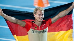 Der deutsche Weitspringer Christian Reif jubelt mit Fahne nach seinem Sieg im Weitsprung © dpa Foto: Bernd Thissen dpa