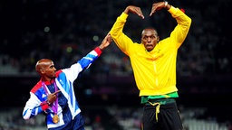 Mohamed Farah (l.) feiert mit Usain Bolt seinen Sieg über 5.000 Meter bei den Olympischen Spielen 2012 in London. © picture alliance / empics Foto: Adam Davy