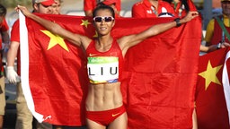 Die chinesische Geherin Liu Hong jubelt mit der China-Flagge. © Imago/Xinhua