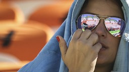 Eine Zuschauerin blickt gespannt auf das Beachvolleyballfeld in Rio. © imago / Fotoarena